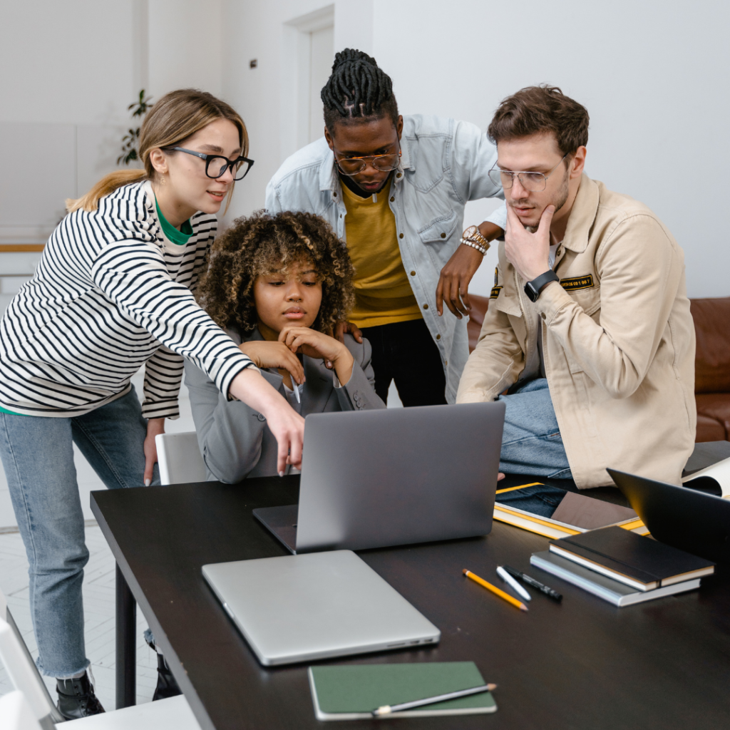 a group of people looking at a laptop in an office